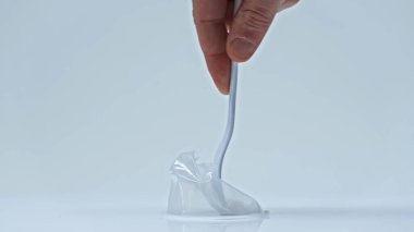 Gri üzerinde tek kullanımlık çatalla plastik bardağa basan adam görüntüsü.