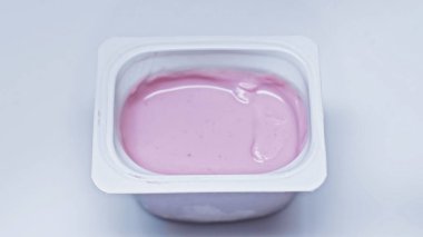 Beyaz üzerinde pembe yoğurt olan plastik kabın üst görüntüsü
