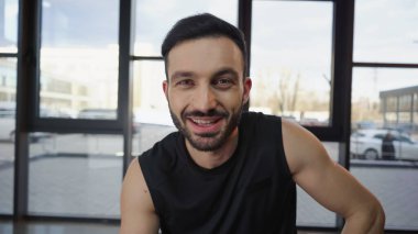 Neşeli sporcu spor salonunda kameraya bakıyor. 