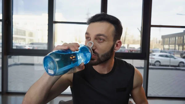 Sportsman drinking water in sports center