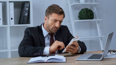 Resmi olarak hesap makinesi kullanan muhasebeci dizüstü bilgisayar ve defter yanında