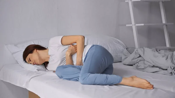 Wanita Berbaring Tempat Tidur Dengan Piyama Dan Menderita Sakit Perut — Stok Foto