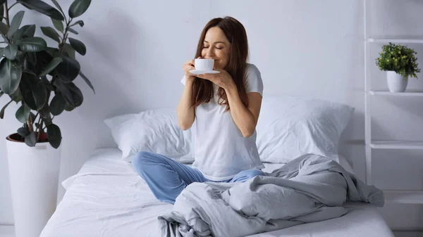 Pleased Woman Pajamas Sitting Bed Smelling Aromatic Coffee — Stock Photo, Image