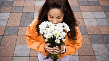 high angle view of happy woman smelling bouquet of white flowers outside 