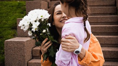 happy mother receiving bouquet of white flowers from daughter 