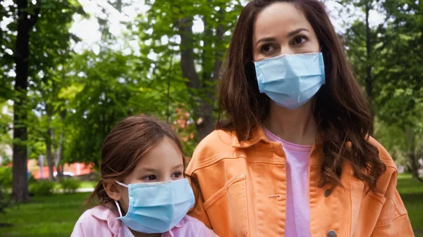 mother and daughter in blue medical masks in park