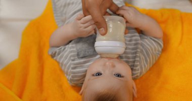 top view of father feeding infant boy with milk in baby bottle