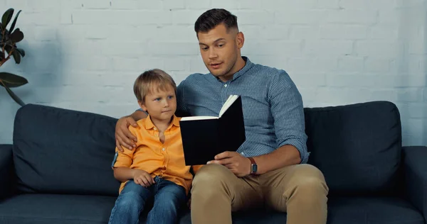 Bel Padre Che Legge Libro Alta Voce Figlio Soggiorno — Foto Stock