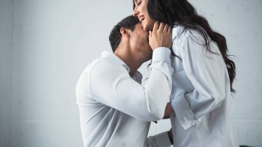 Beyaz gömlekli iş adamı. Evinde mutlu bir kadını kucaklıyor ve öpüyor.