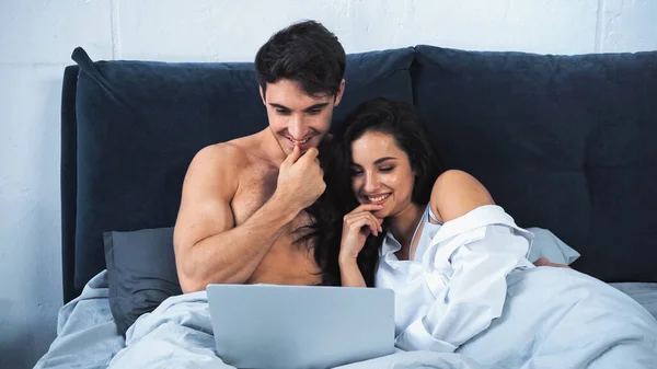 Happy Shirtless Man Cheerful Woman Watching Comedy Movie Laptop Bed — стоковое фото