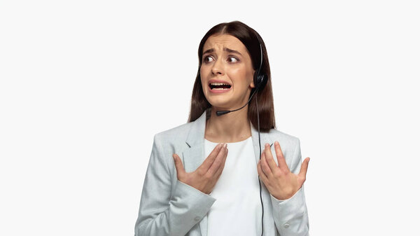 tensed operator in headset and grey blazer talking in microphone isolated on white