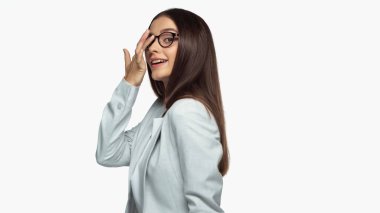 cheerful businesswoman in grey blazer adjusting eyeglasses isolated on white