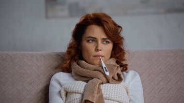 Eşarplı hasta ve kıvırcık kadın. Sıcaklığı elektronik termometreyle ölçüyor.