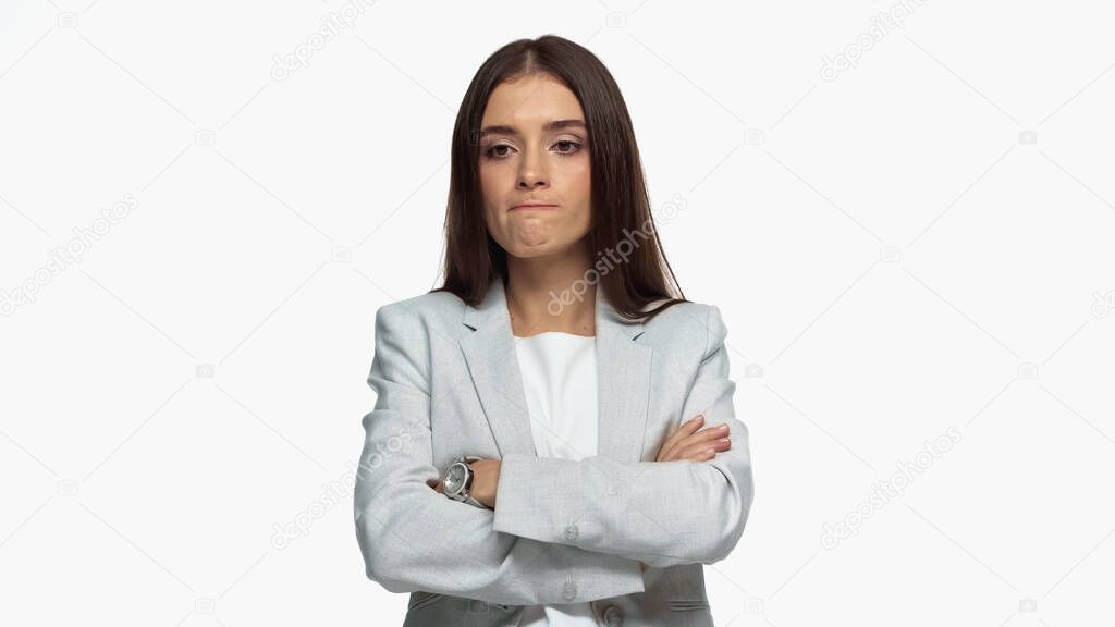 displeased businesswoman in grey blazer standing with crossed arms isolated on white