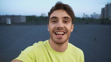 Cheerful sportsman looking at camera on roof in evening 