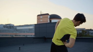 Young brunette sportsman working out on roof in evening 