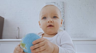 cute toddler girl with blue eyes holding small globe