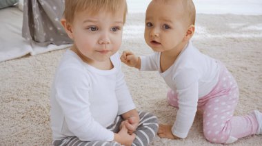 toddler sister and brother sitting together on carpet at home