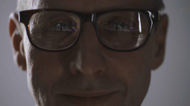 close up view of cheerful middle aged man in eyeglasses looking at camera isolated on grey
