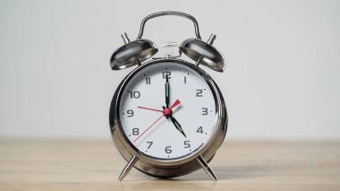 metallic and vintage alarm clock on wooden table isolated on grey 