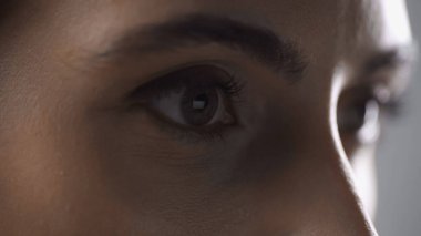 close up view of woman mascara on eyelashes looking away isolated on grey