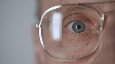 cropped view of middle aged man with blue eye and eyeglasses looking at camera isolated on grey  clipart