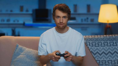 KYIV, UKRAINE - MARCH 12, 2019: concentrated young man playing video game in living room 
