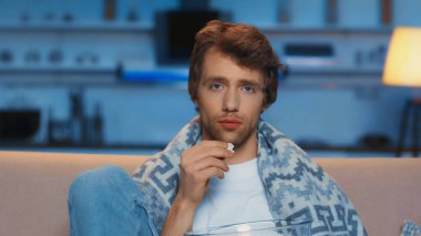 young man holding popcorn near bowl while watching movie in living room 