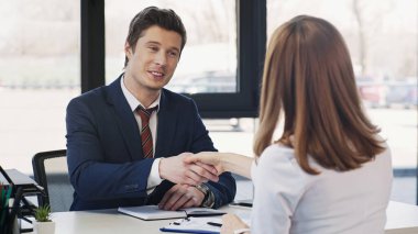 pleased businessman shaking hands with woman after job interview