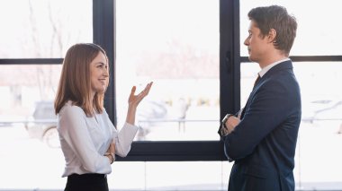 side view of businessman standing with crossed arms while listening to woman on job interview