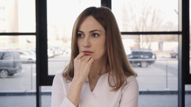 worried woman holding hand near chin and looking away before job interview