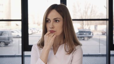 worried woman holding hand near chin and looking away before job interview clipart