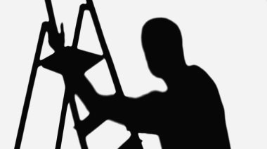 black shadow of ladder near silhouette of repairman isolated on white
