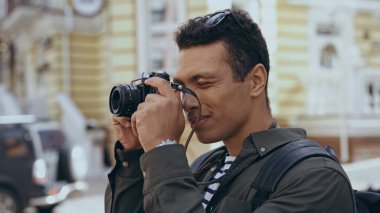Bi-racial traveler taking photo on film camera on street 