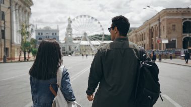 Multiethnic travelers with backpacks walking on european street 