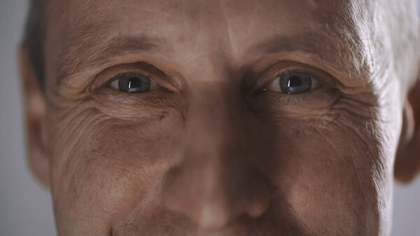 close up view of happy middle aged man with wrinkles looking at camera isolated on grey 
