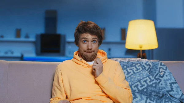 Scared Young Man Yellow Hoodie Grimacing While Watching Movie Living — Stockfoto