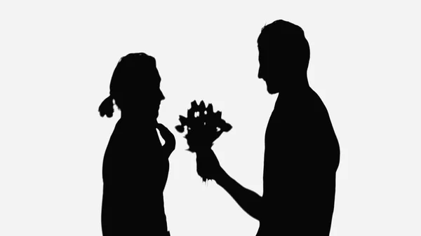 shadows of man with flowers and surprised woman pointing with hand at herself isolated on white