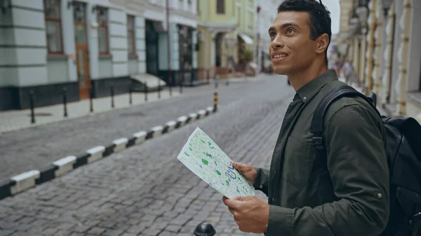 Smiling Racial Man Holding Map Looking Away Street — стоковое фото