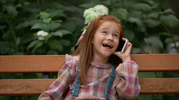 Positive Child Talking Smartphone While Sitting Bench Park Foto Stock