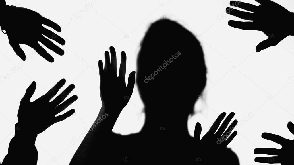 shadows of hands of people near bullied woman gesturing isolated on white
