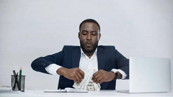 African american businessman holding dollar banknotes isolated on grey — Stock Photo