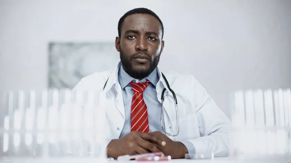 Афроамериканський вчений, що сидить біля розмитих пробірки в лабораторії — стокове фото