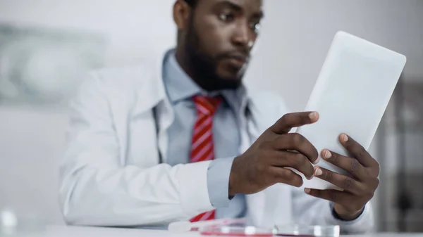 Doctor afroamericano borroso usando tableta digital - foto de stock