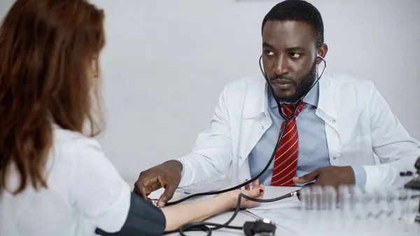 Afrikanische amerikanische Ärztin untersucht rothaarige Frau — Stockfoto