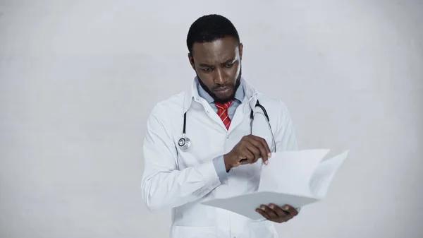 African american doctor holding folder with papers isolated on grey — Stock Photo