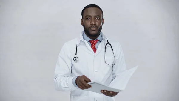 African american doctor holding folder with document isolated on grey — Stock Photo