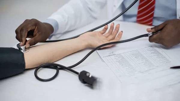 Vista ritagliata di afro-americano medico esaminando donna — Foto stock