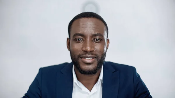 Cheerful african american businessman looking at camera on grey — Stock Photo