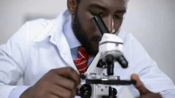 African american scientist looking through microscope in laboratory — Stock Photo